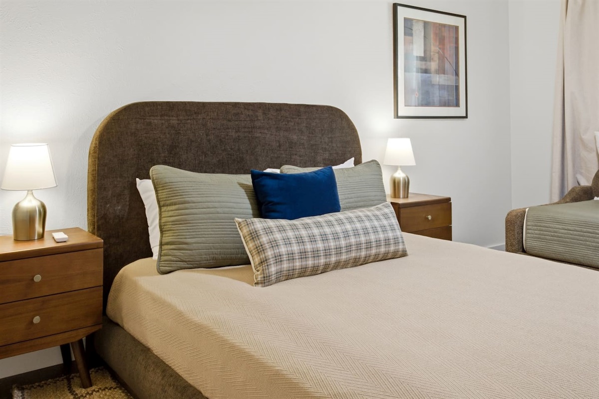 Spacious guest bedroom offering a queen bed and a twin bed, paired with room-darkening shades and cozy bedding for a comfortable and versatile sleep arrangement.