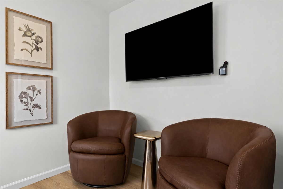 Cozy seating nook with plush chairs and wall-mounted TV—perfect for unwinding, reading, or enjoying a quiet evening in comfort.
