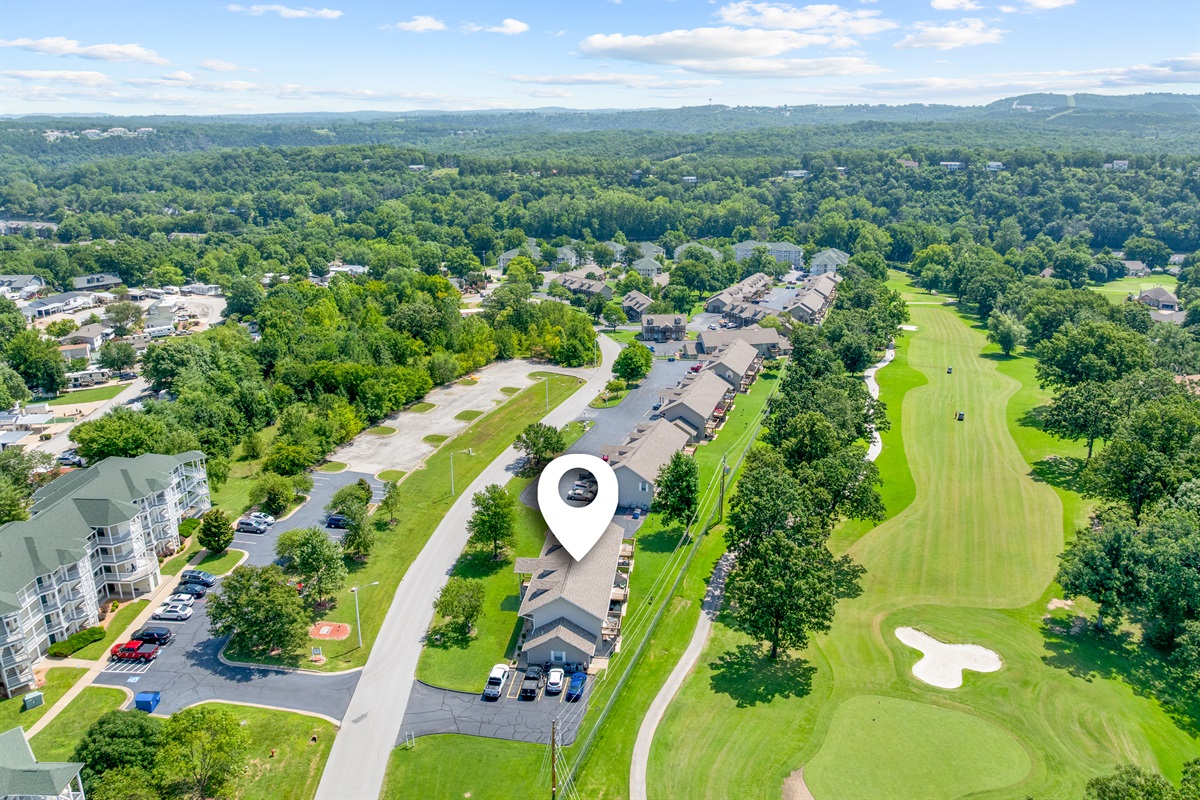 Aerial view pinpointing your condo—steps from parking with a golf course backdrop.