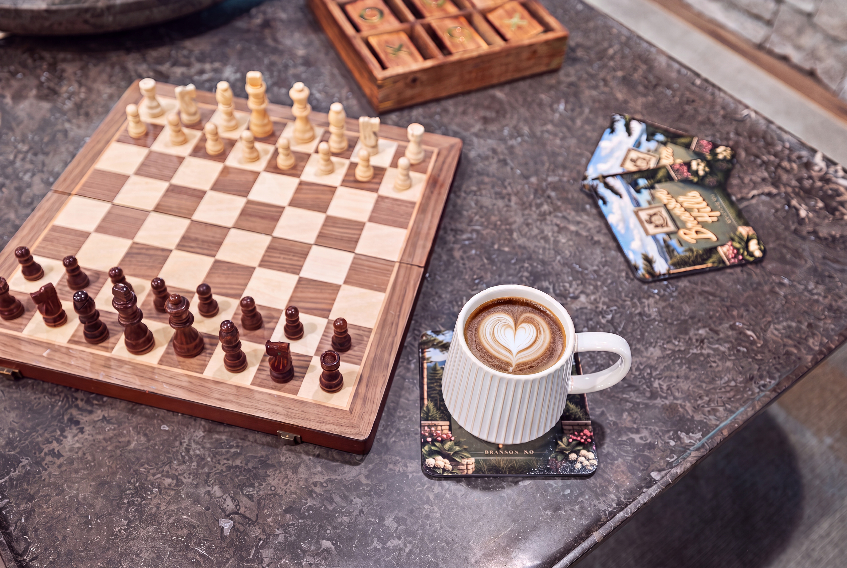 A carved chess set and a fresh latte for a slow, unhurried afternoon.