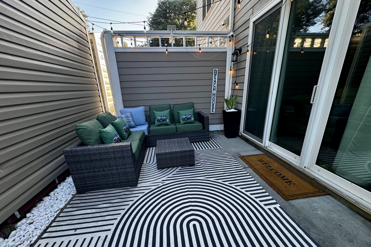 Private outdoor patio with cushioned lounge seating and string lights — golden-hour evenings covered