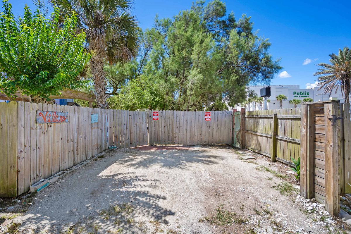 The parking area sits behind the fence, screened from the road. There is one space per unit, so look for the stained glass sea turtles and jellyfish hung on the fence to know you are in exactly the right spot.