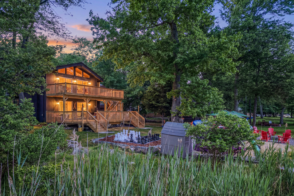 Élevé Lake Lodge at twilight — two decks, warm interior glow, and wooded lakefront setting
