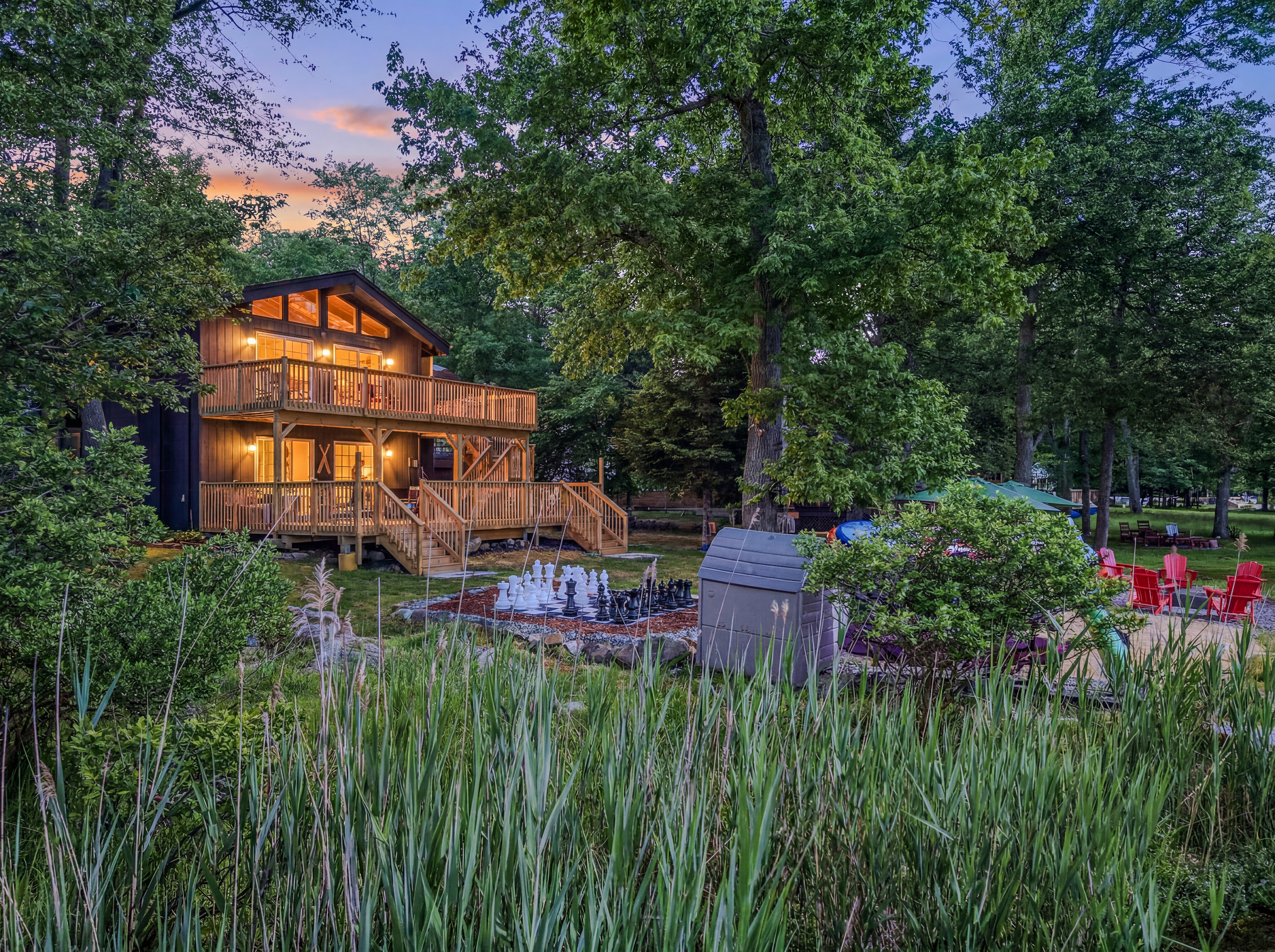 Élevé Lake Lodge at twilight — two decks, warm interior glow, and wooded lakefront setting
