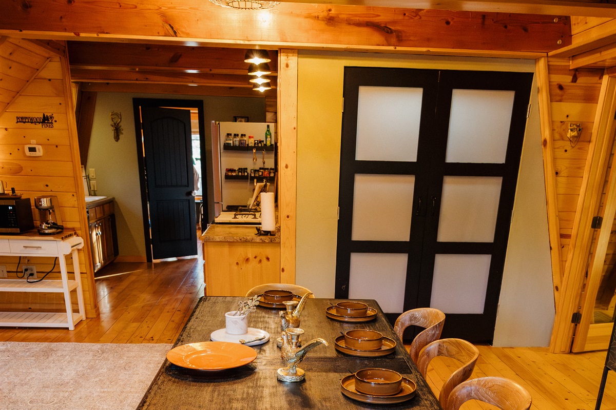 Gothic western dining with handcrafted wood table seating 12+ in this Show Low cabin. Warm pine walls and modern barn doors blend rustic charm with luxury. Fully equipped kitchen perfect for family meals and group gatherings in the White Mountains.