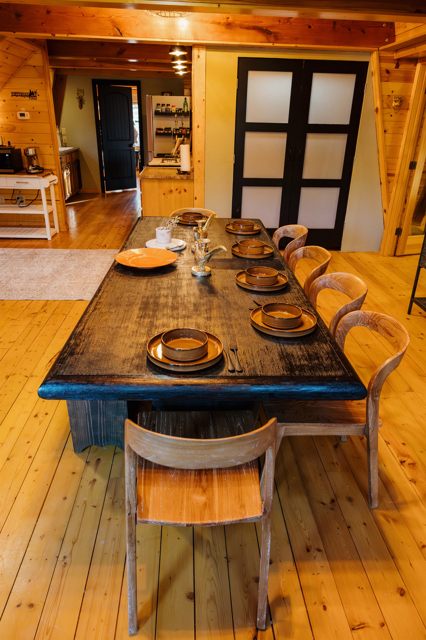 Gothic western dining with handcrafted wood table seating 12+ in this Show Low cabin. Warm pine walls and modern barn doors blend rustic charm with luxury. Fully equipped kitchen perfect for family meals and group gatherings in the White Mountains.