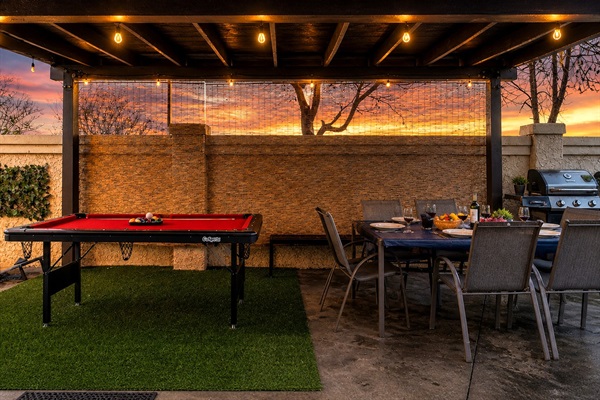 Pool table and dining table under a covered patio, adjacent to the grill—perfect for group gatherings