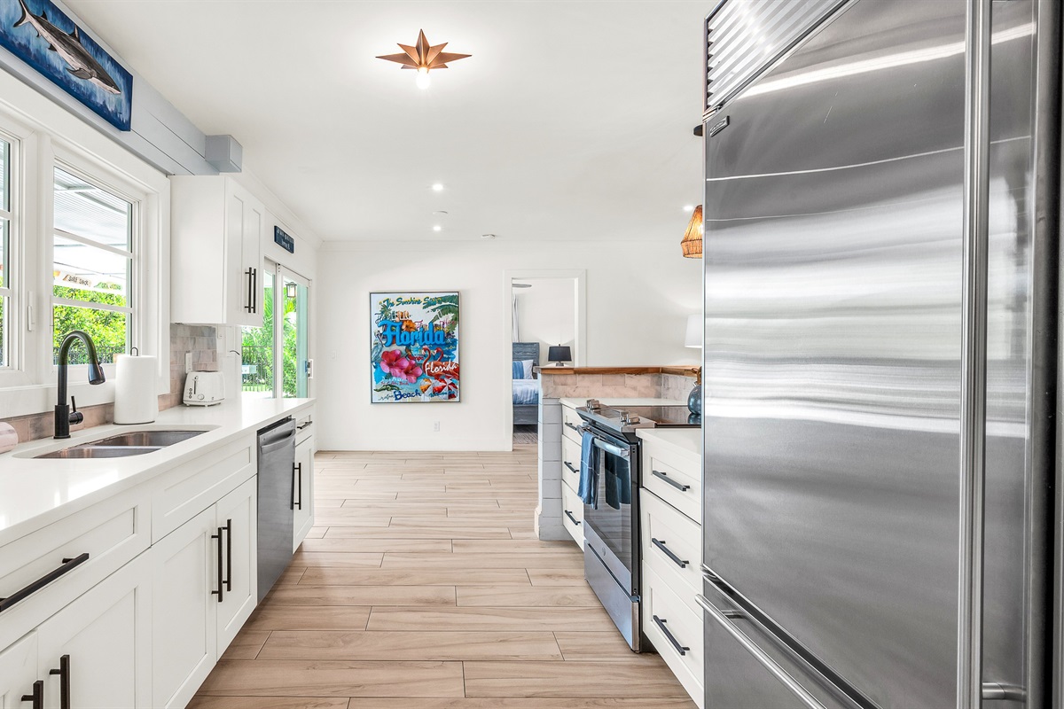 The fully stocked kitchen boasts a Sub-Zero fridge and acacia wood butcher block counters. A peninsula with seating provides the perfect spot for casual meals or morning coffee.