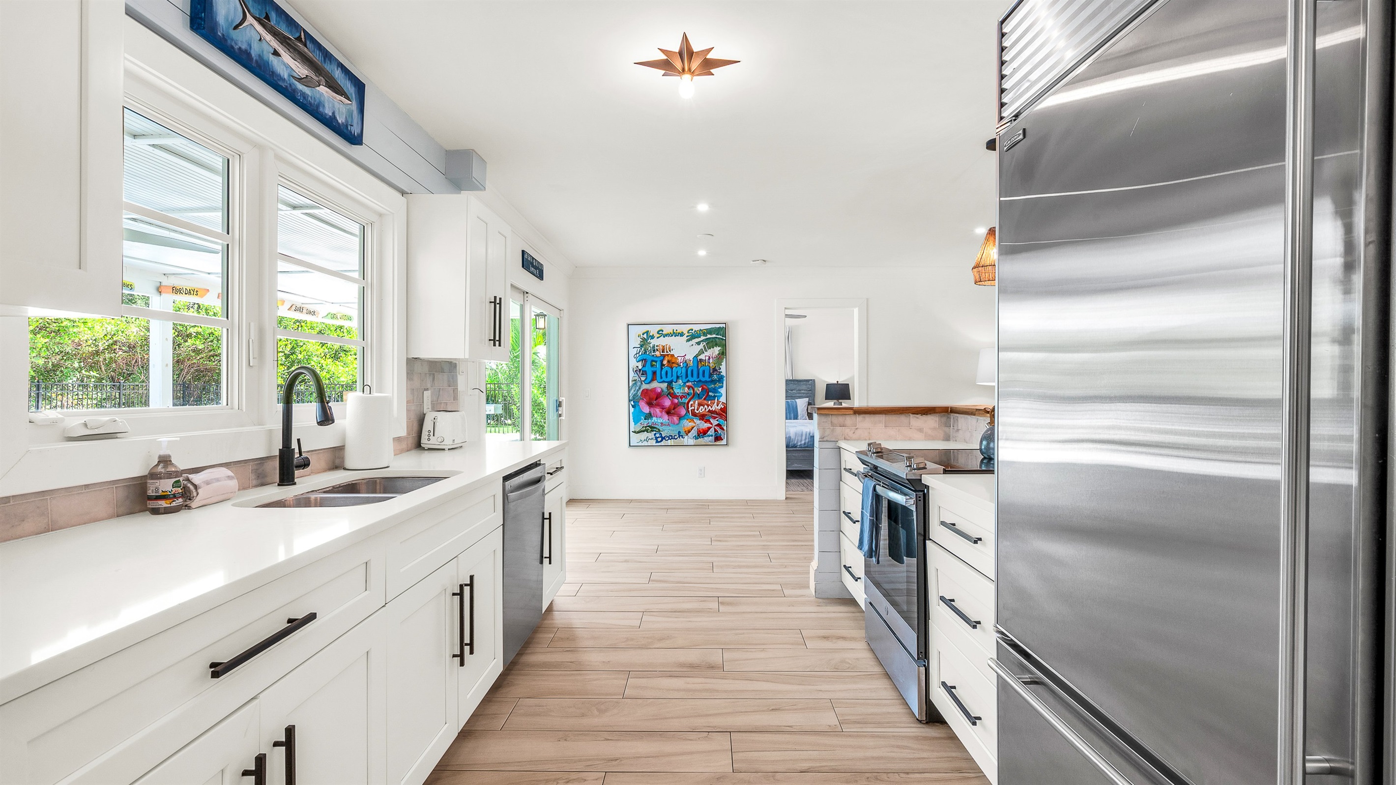 The fully stocked kitchen boasts a Sub-Zero fridge and acacia wood butcher block counters. A peninsula with seating provides the perfect spot for casual meals or morning coffee.