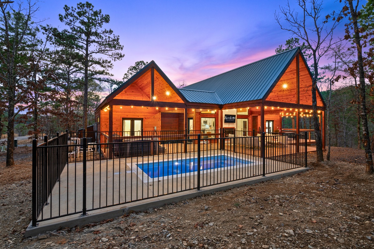 With tall windows, warm lighting, and a fenced pool area just steps away, the cabin offers a welcoming space that blends indoor comfort with outdoor fun.