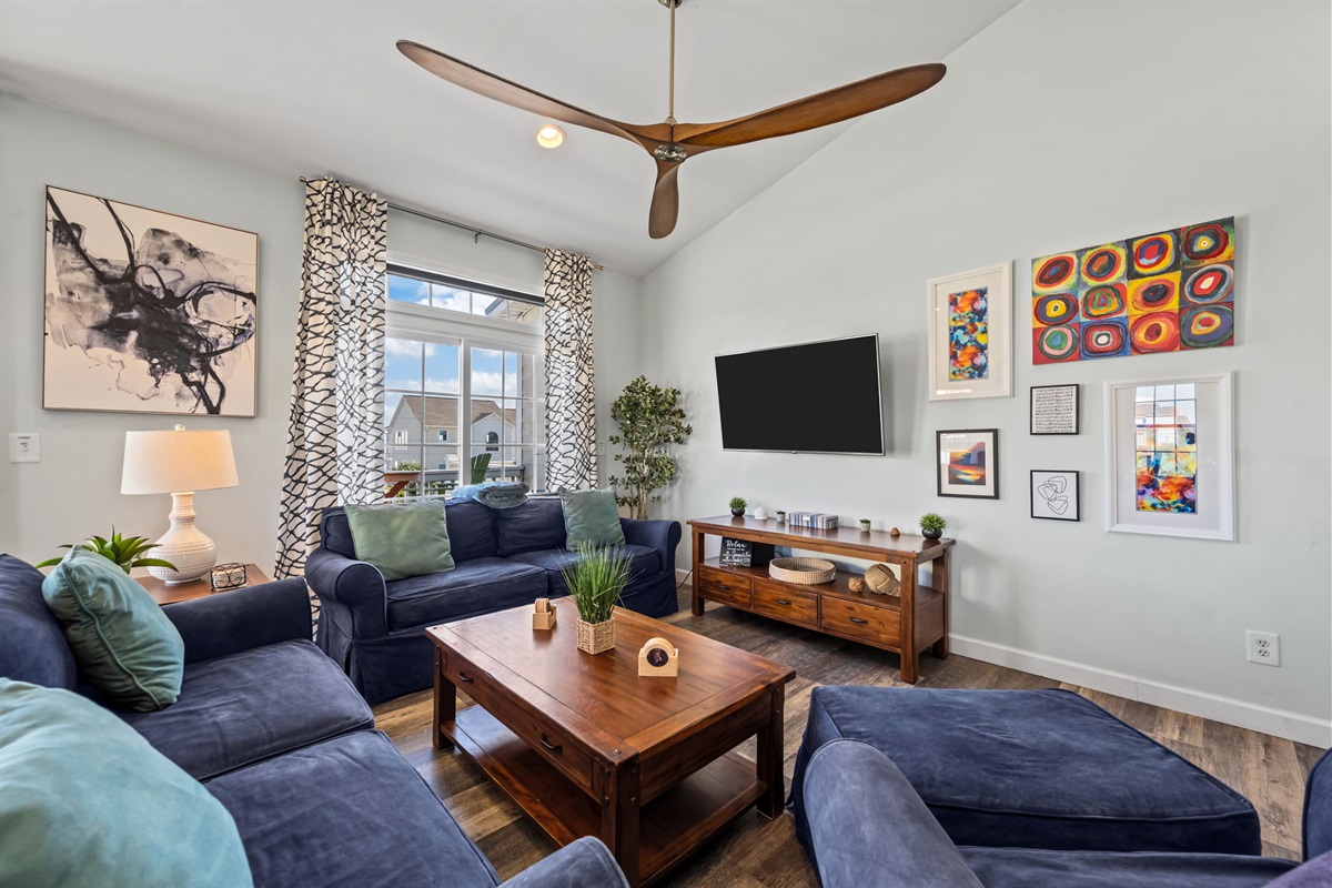 The common area flows seamlessly toward a dining section and the living room illuminated by natural light from the windows.