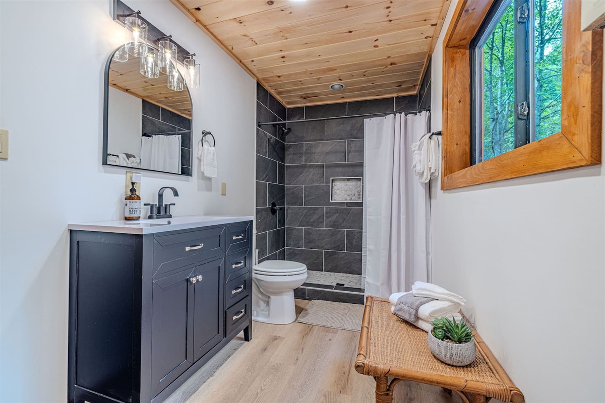 Conveniently connected to the main-floor queen bedroom and accessible to downstairs guests, this newly refreshed bath features a sleek single vanity and a beautifully tiled walk-in shower.
