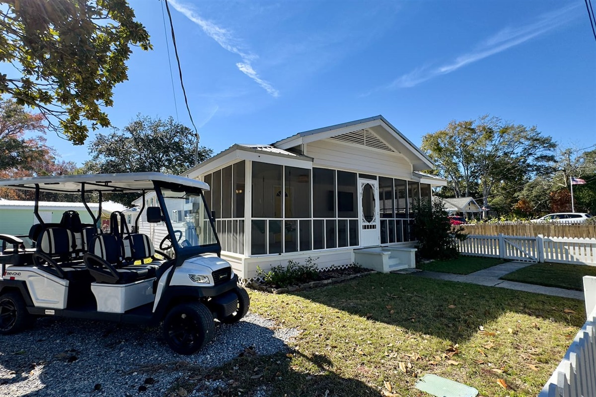 Charming cottage exterior with a screened porch, private yard, and convenient golf cart access.