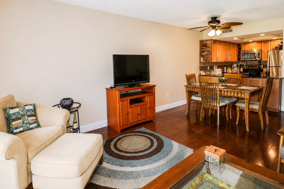 Inviting open layout with beige armchair, wood dining table, and modern kitchen.