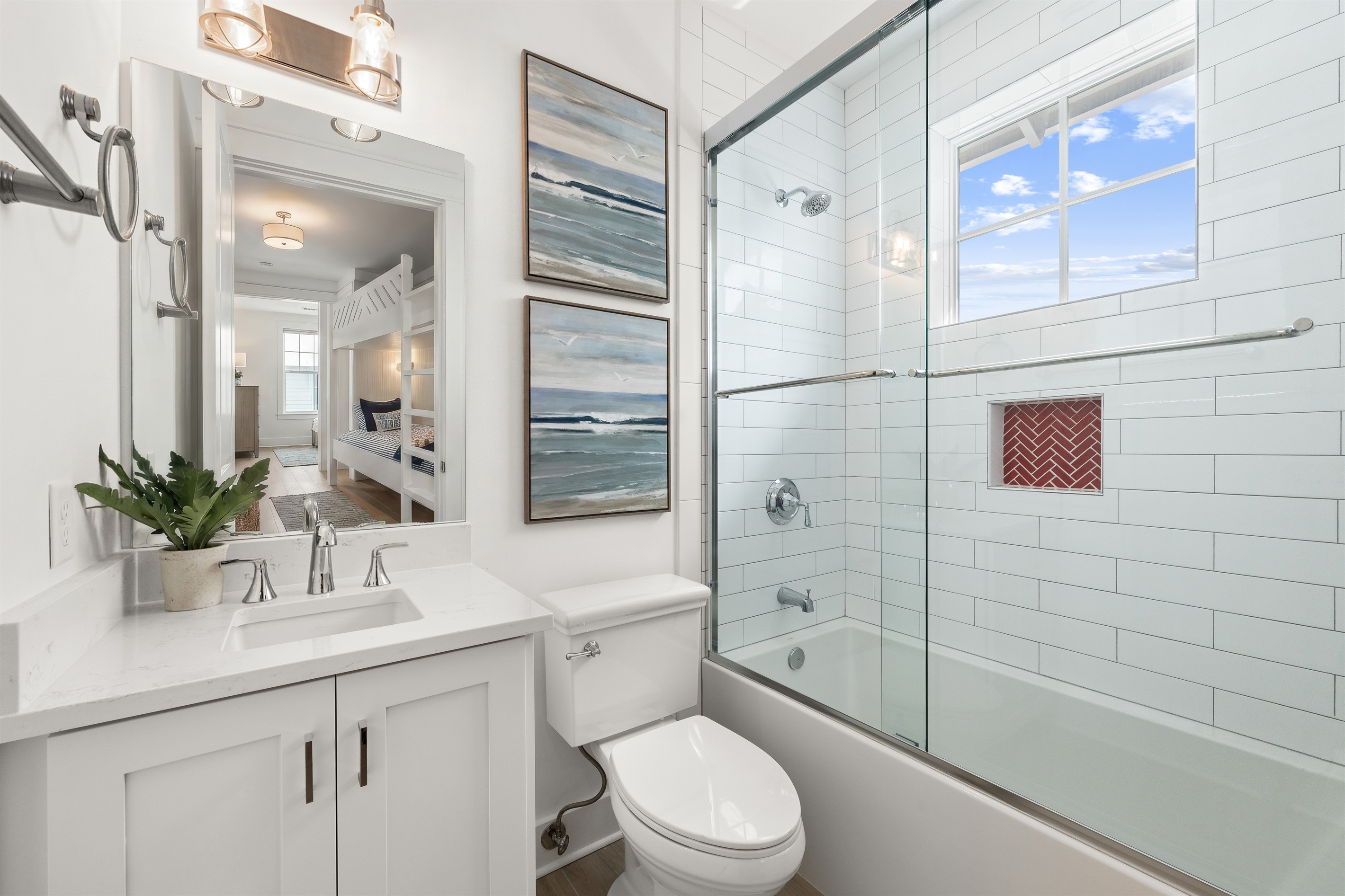 This private ensuite bathroom features bright finishes and a clean coastal aesthetic, providing comfort and convenience for guests staying in the bunk room.