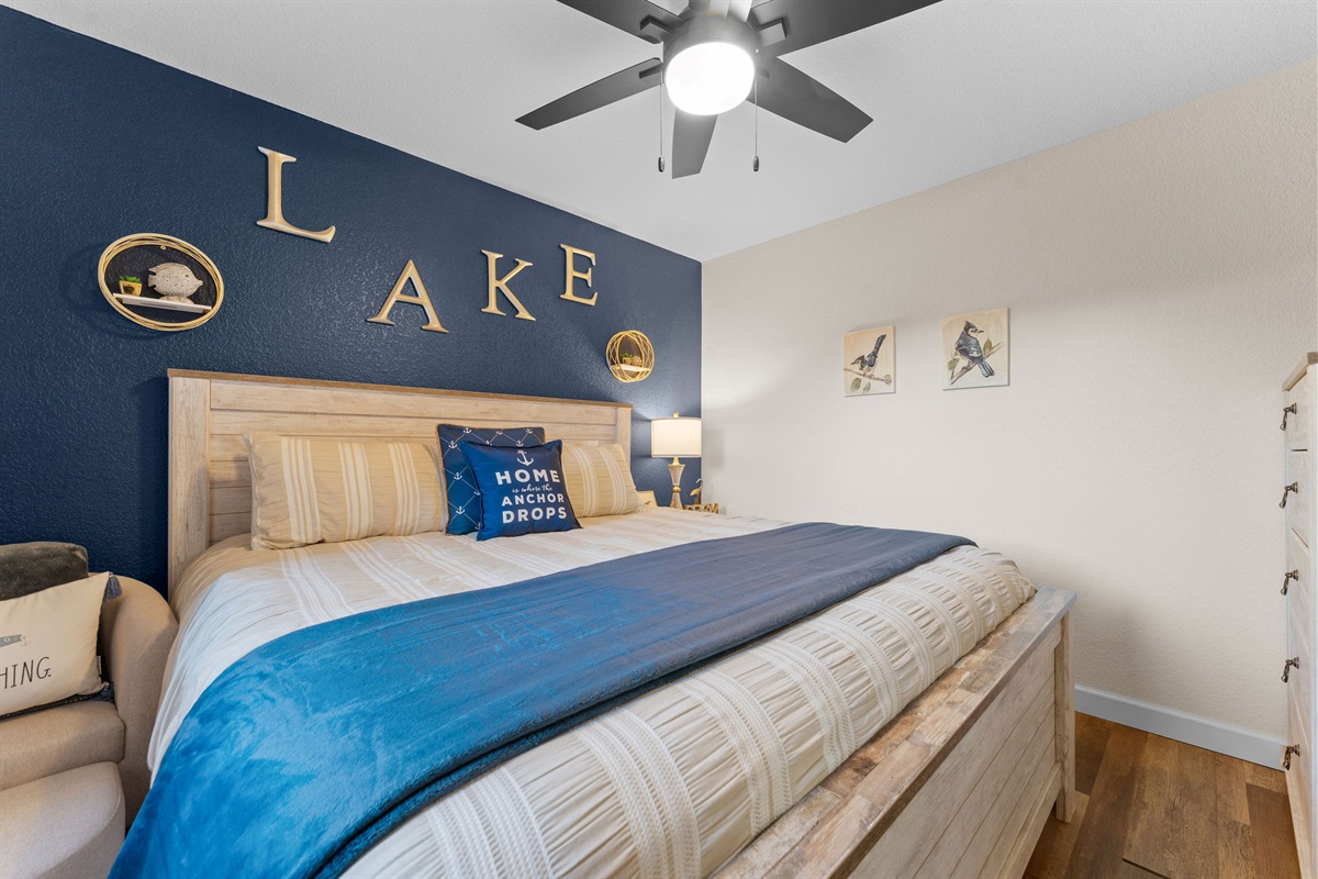Cozy bedroom with king bed, accent wall, and ceiling fan.
