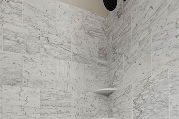 A newly installed, modern tiled shower/tub combo with a fresh and stylish design.