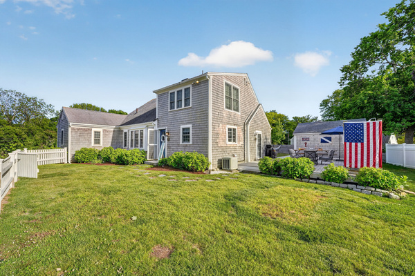 Beautiful exterior view showcasing the home's spacious yard, classic Cape Cod charm, and inviting outdoor spaces.