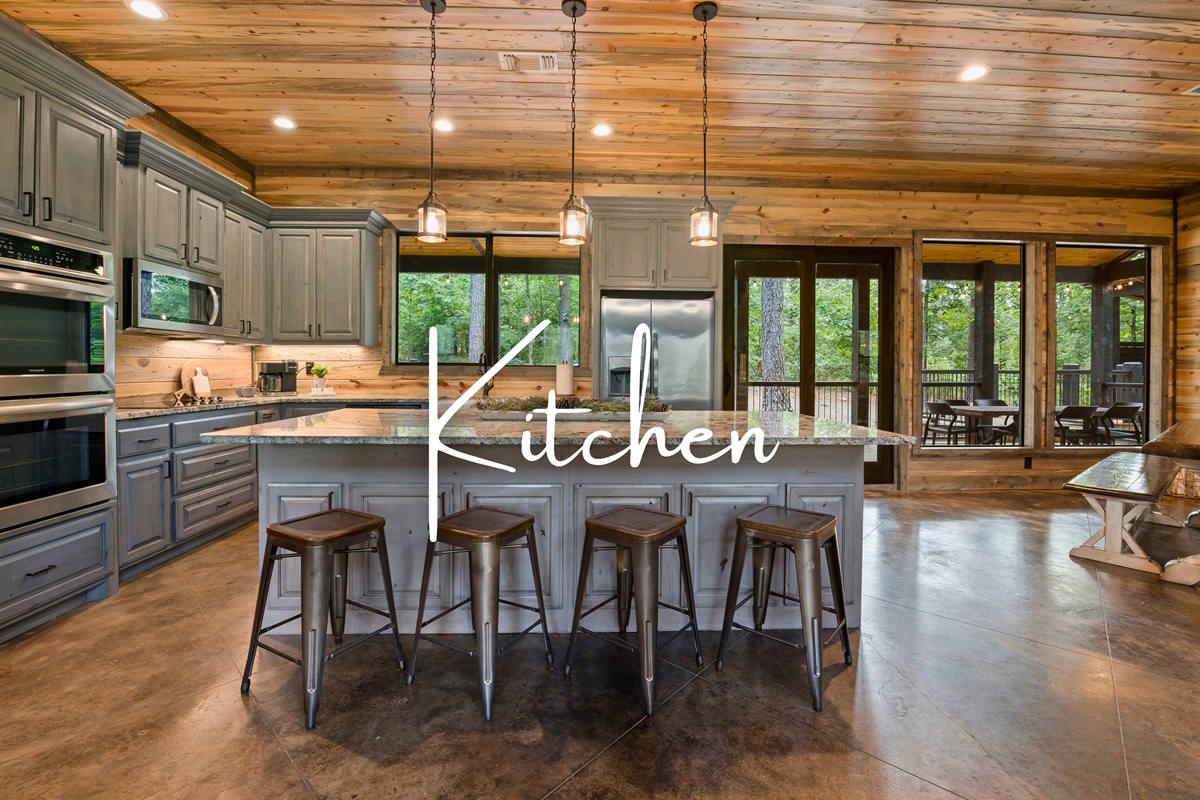 Prepare and enjoy meals in this spacious kitchen with modern appliances, a large island with seating, and an open layout that extends into a relaxing outdoor dining area.