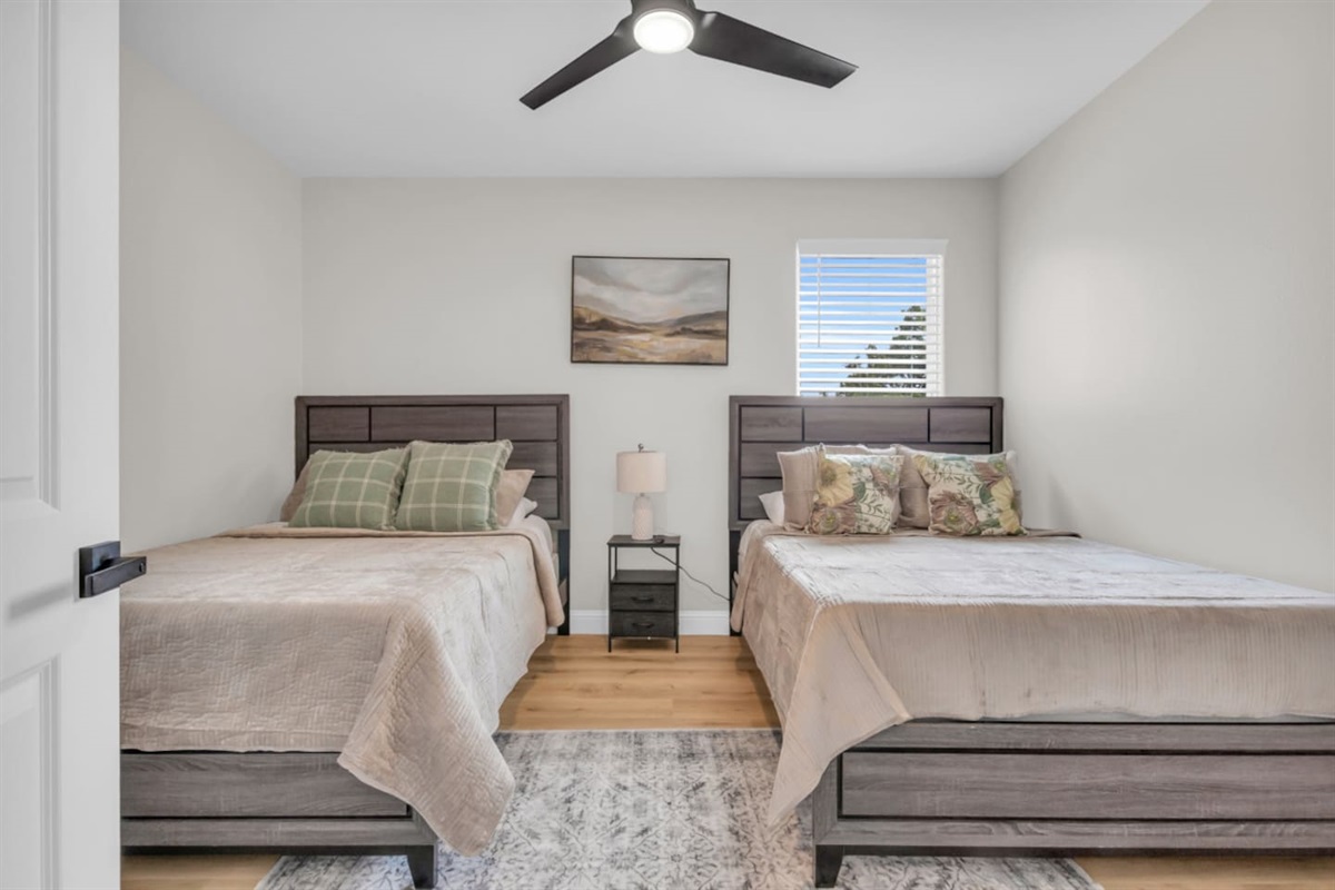 Guest bedroom with queen beds and ceiling fan comfort.