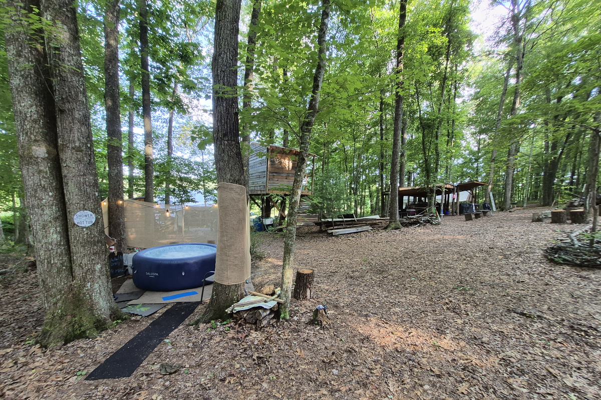 This shows the treehouse shower and outdoor kitchen behind the hot tub area