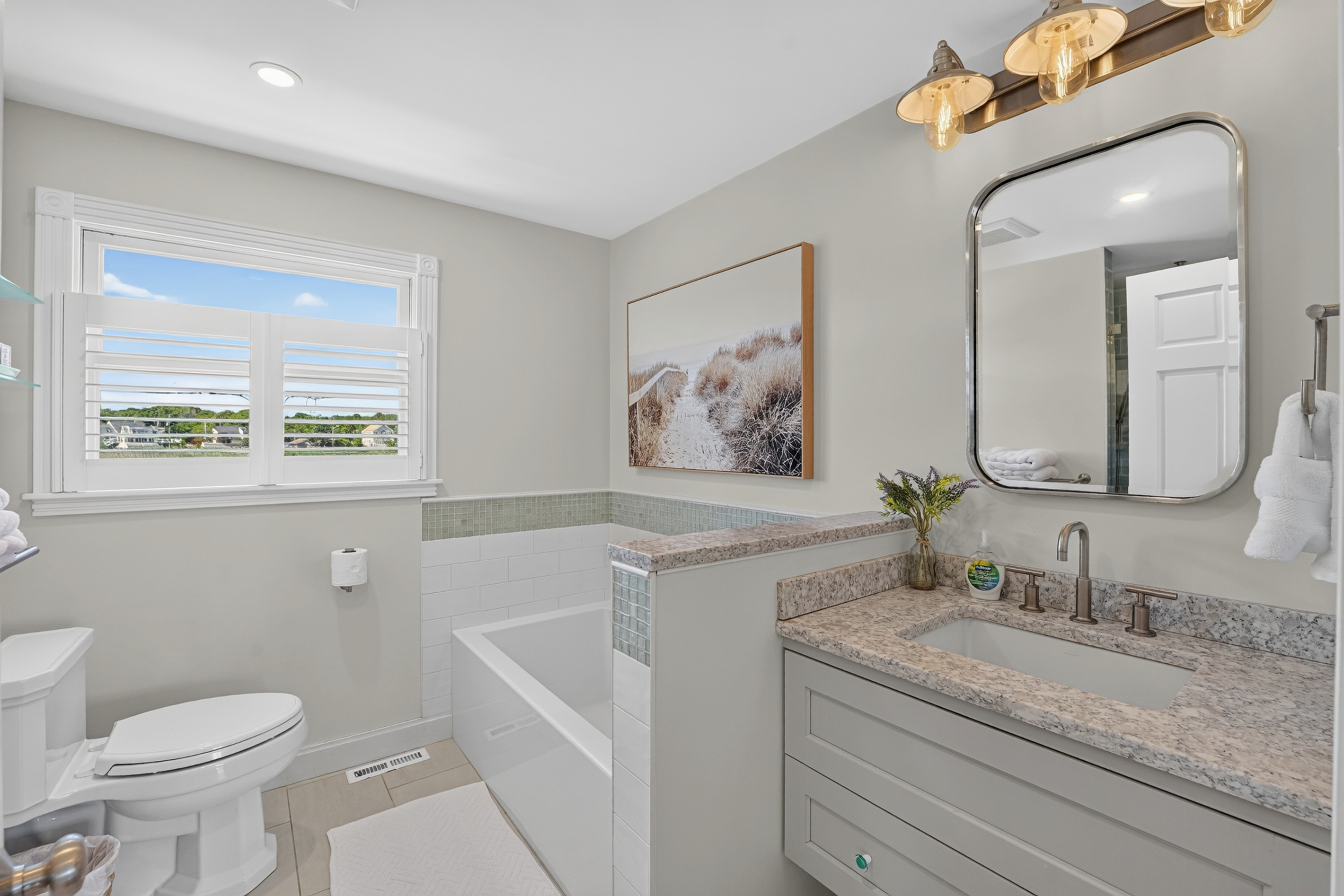 Bright full bathroom with a spacious vanity, bathtub, and plenty of natural light.