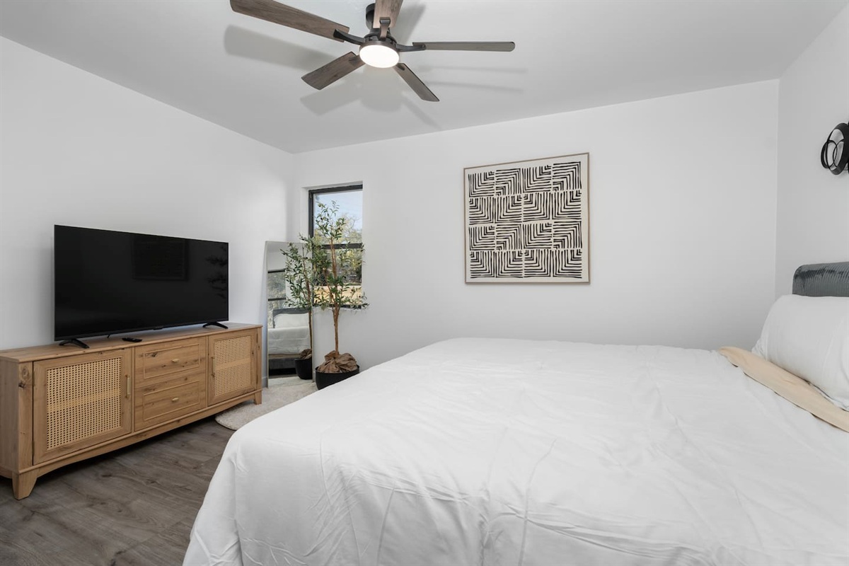 A calm and comfortable room featuring a King bed, TV with streaming channels, a ceiling fan, and crisp bed linens. Ideal for quiet nights in and a great night’s sleep.