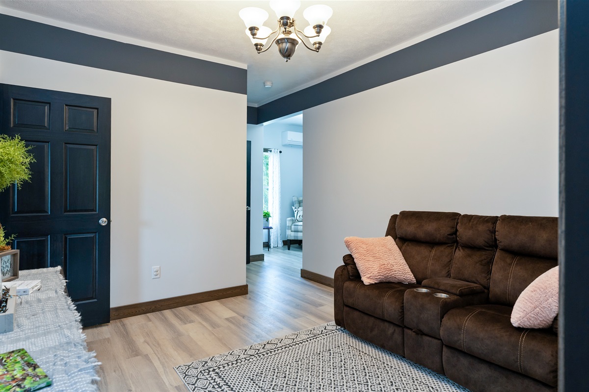 Cozy upstairs common area featuring a plush recliner sofa, soft accents, and modern flooring, ideal for relaxing evenings at home.