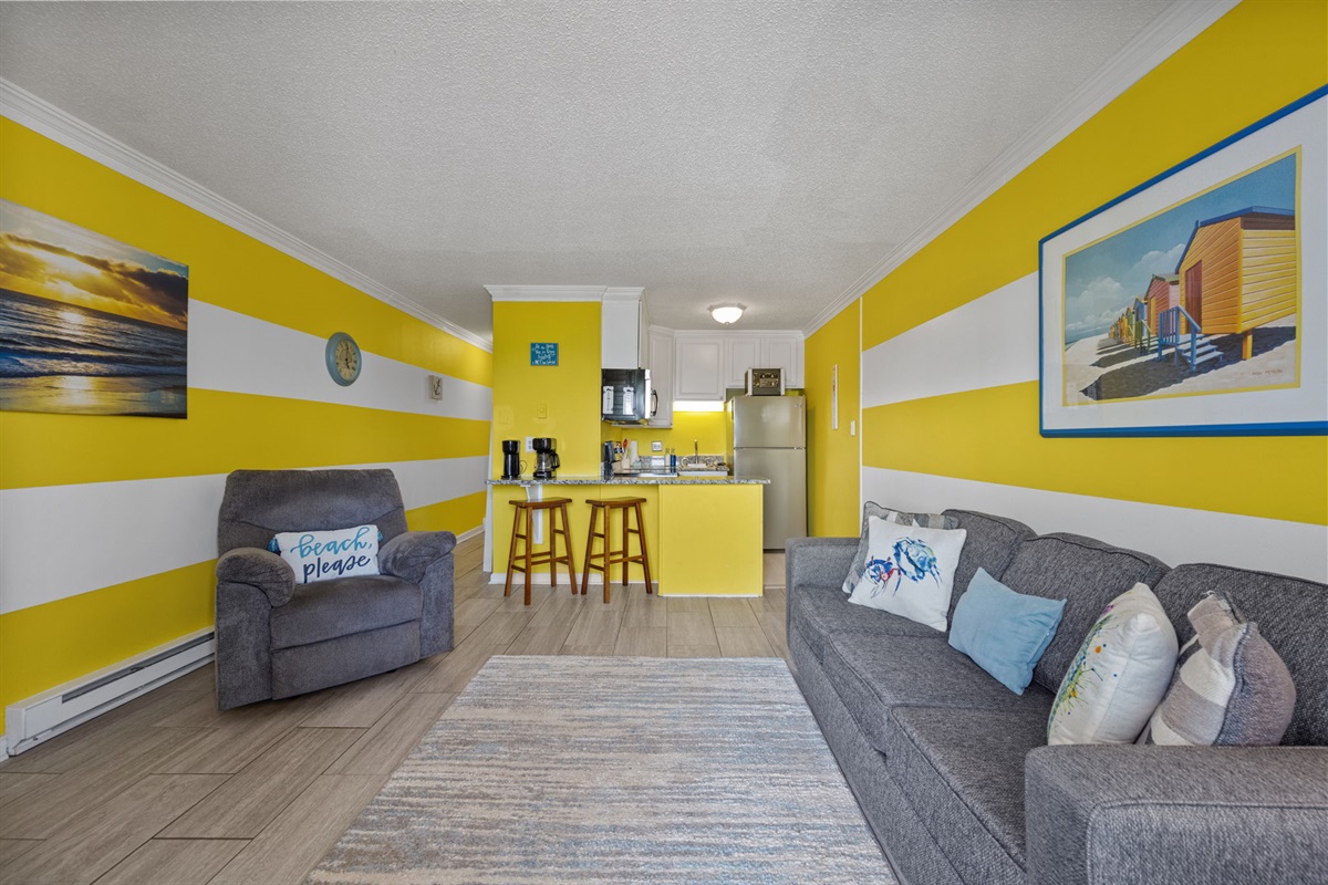 Open living area with bold coastal stripes, comfy seating, and an easy flow into the kitchen