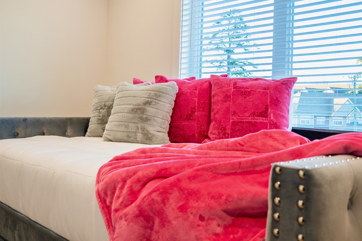 This vibrant queen bedroom features plush bedding, bold accents, and natural light, creating a stylish and relaxing retreat.