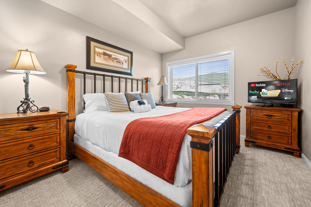 An inviting bedroom with a queen bed and a large window for fresh mountain air.