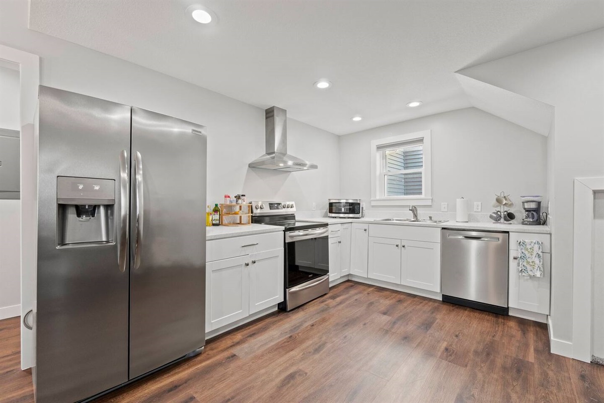 Fully equipped kitchen with a fridge, oven, stove, coffee maker, microwave, and all the essentials for a home-cooked meal.