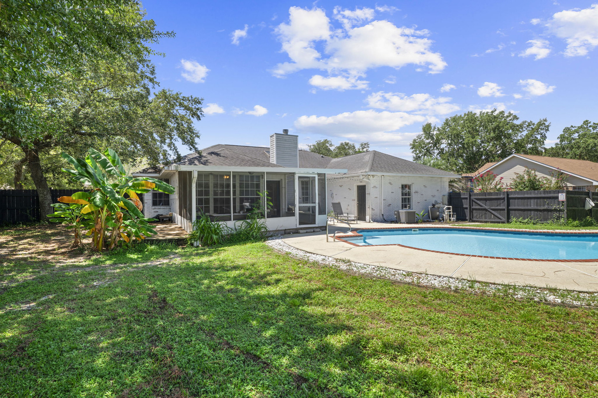 A private, fenced backyard oasis with mature landscaping, a screened porch, and a sparkling pool to enjoy.