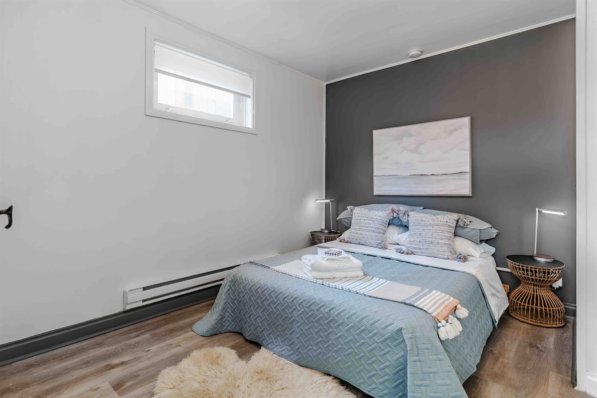 Comfortable basement bedroom with queen bed and soft lighting