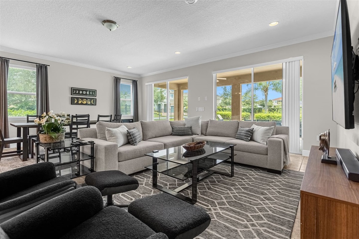 Spacious living room featuring a large L-shaped sofa, reclining chairs, a center table, and a TV with streaming services for ultimate comfort and entertainment.