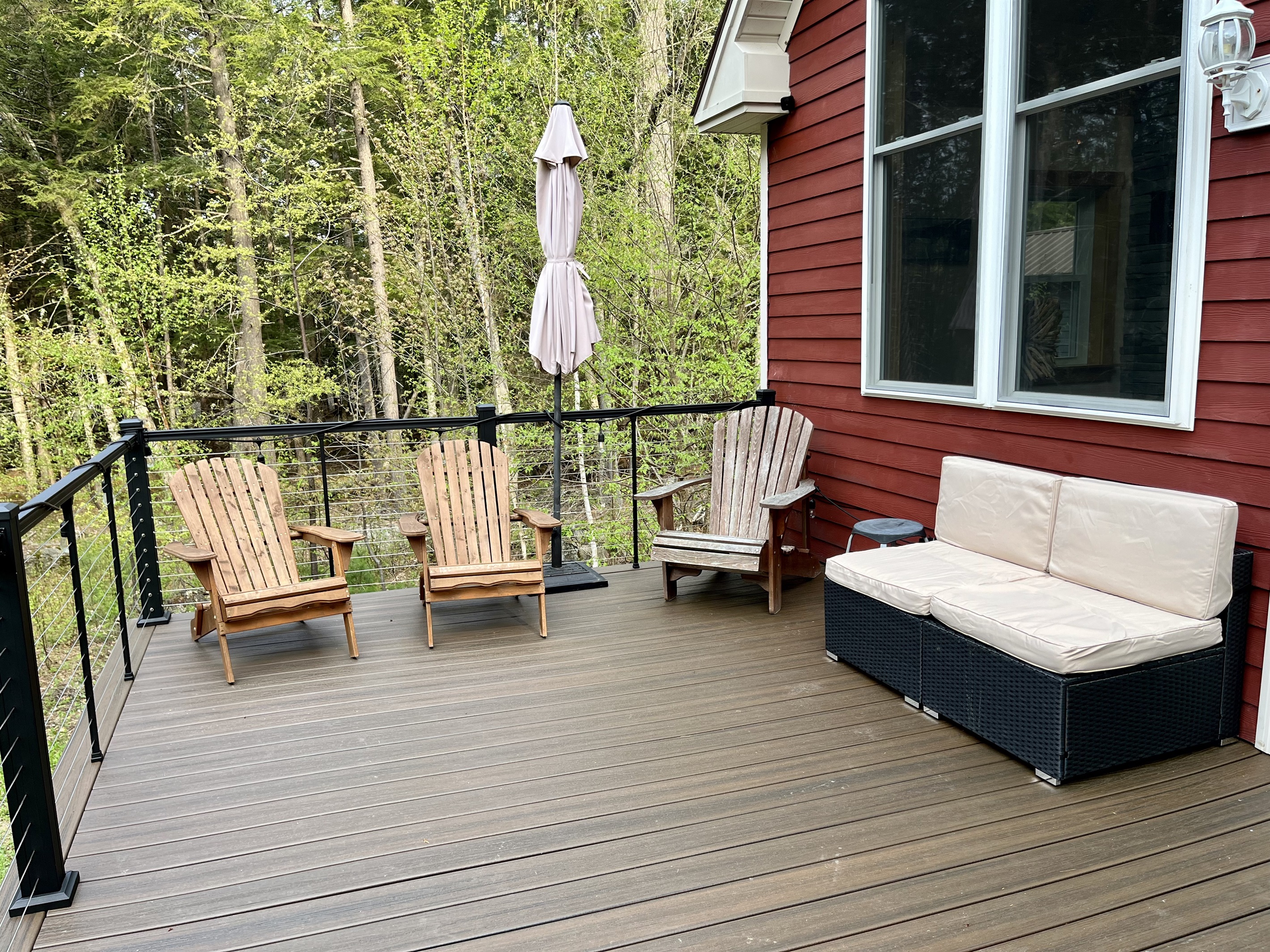 Deck overlooking the lake with outdoor furniture, umbrella, and solo stove.