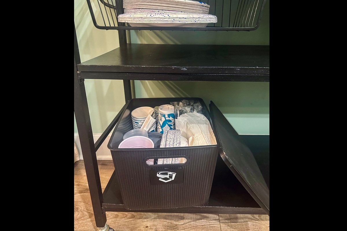 Under-cart kitchen storage stocked with disposable essentials including paper plates, plastic cups, napkins, and utensils for added convenience.