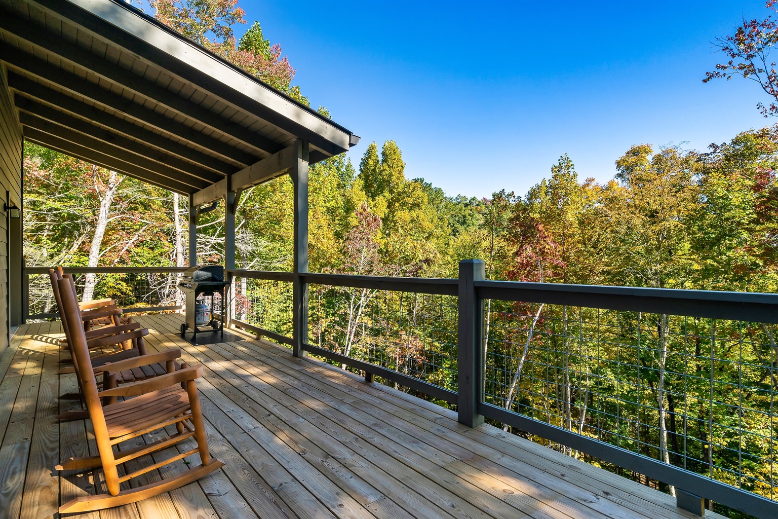 Rocking chairs, a gas grill, and peaceful wooded views await on the covered deck.