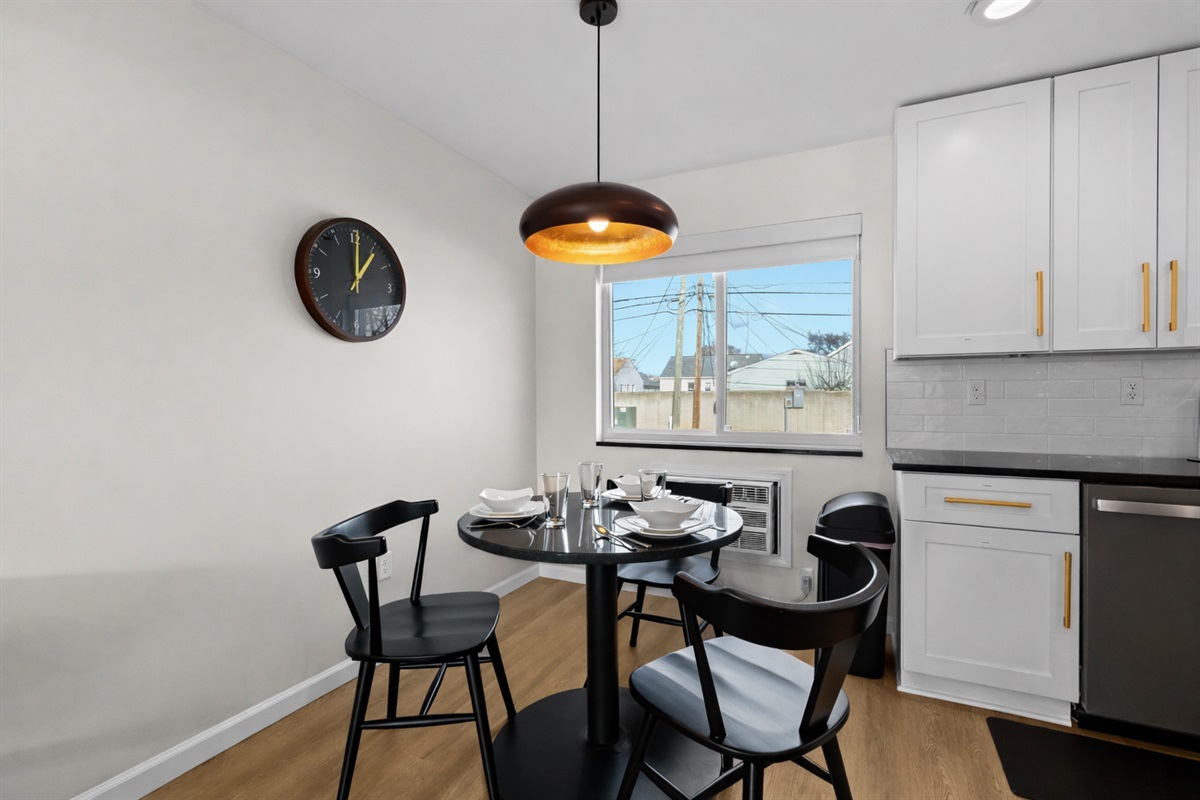 Modern dining nook with stylish seating, warm pendant lighting, and a bright window—perfect for enjoying meals or morning coffee.