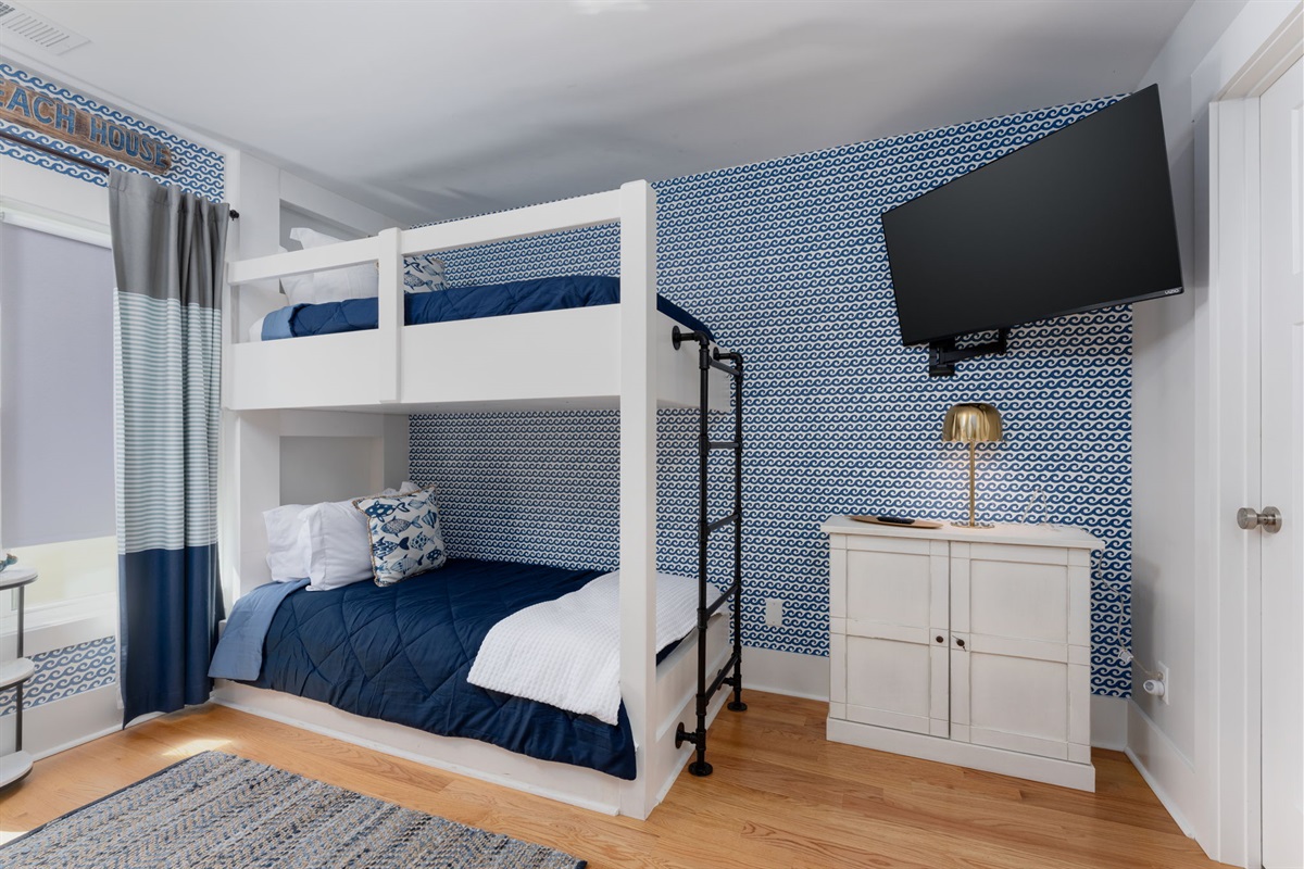 Alternate view of the bunk room with TV and storage, designed for comfort and flexibility.