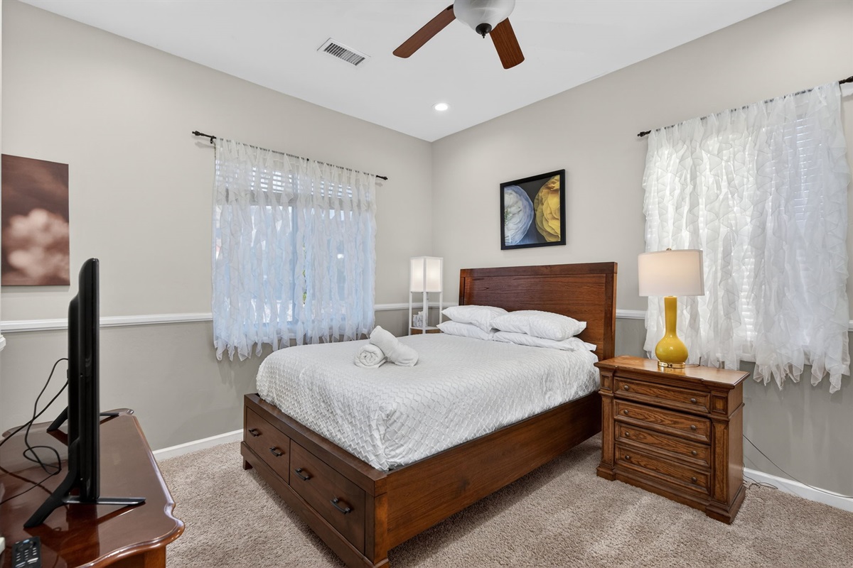 Inviting queen bedroom with Smart TV and soft natural light creates a relaxing private guest retreat