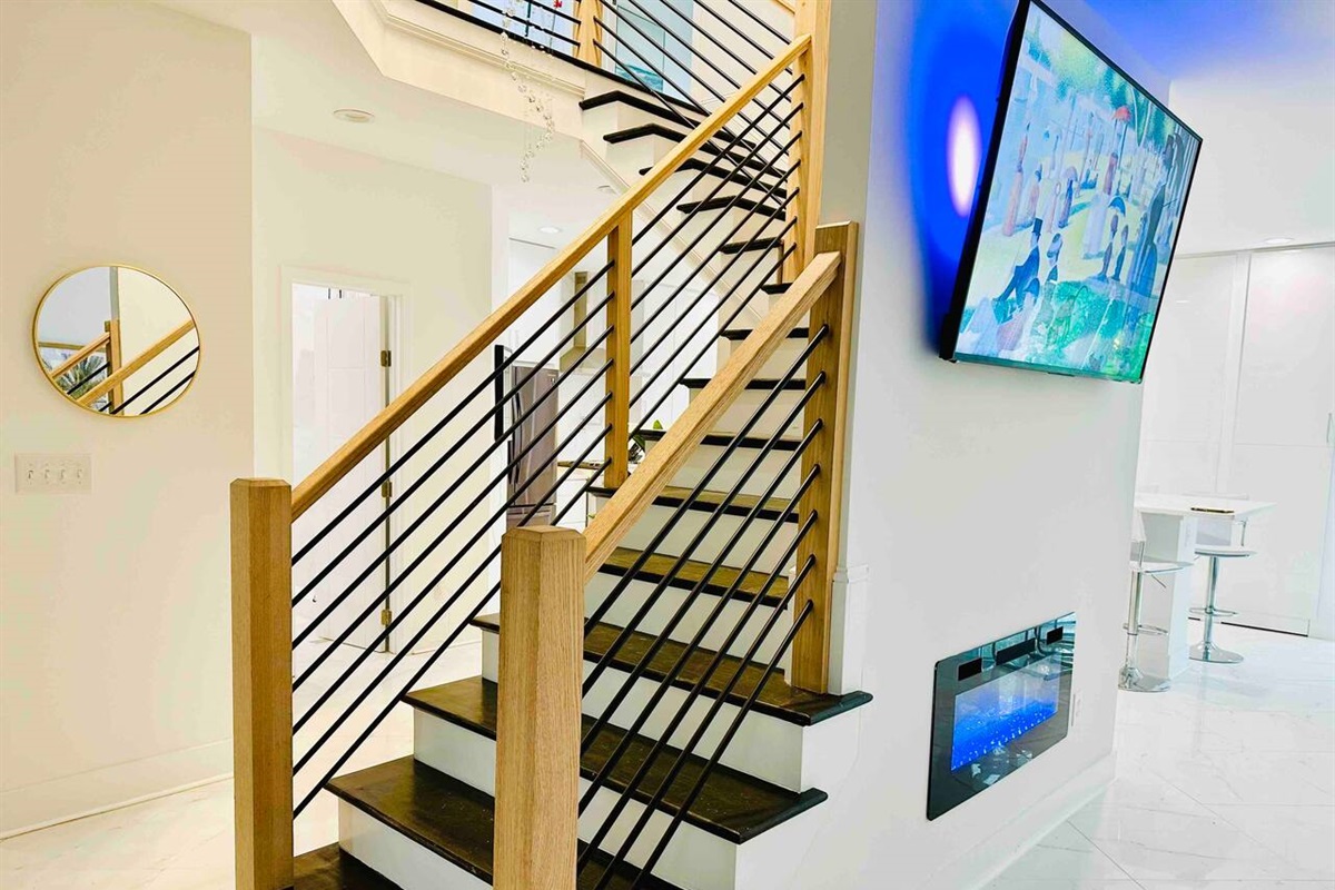 A central stairwell also serves as a central art piece for the home! LED-backlit TV and electric fireplace in the main floor living room.