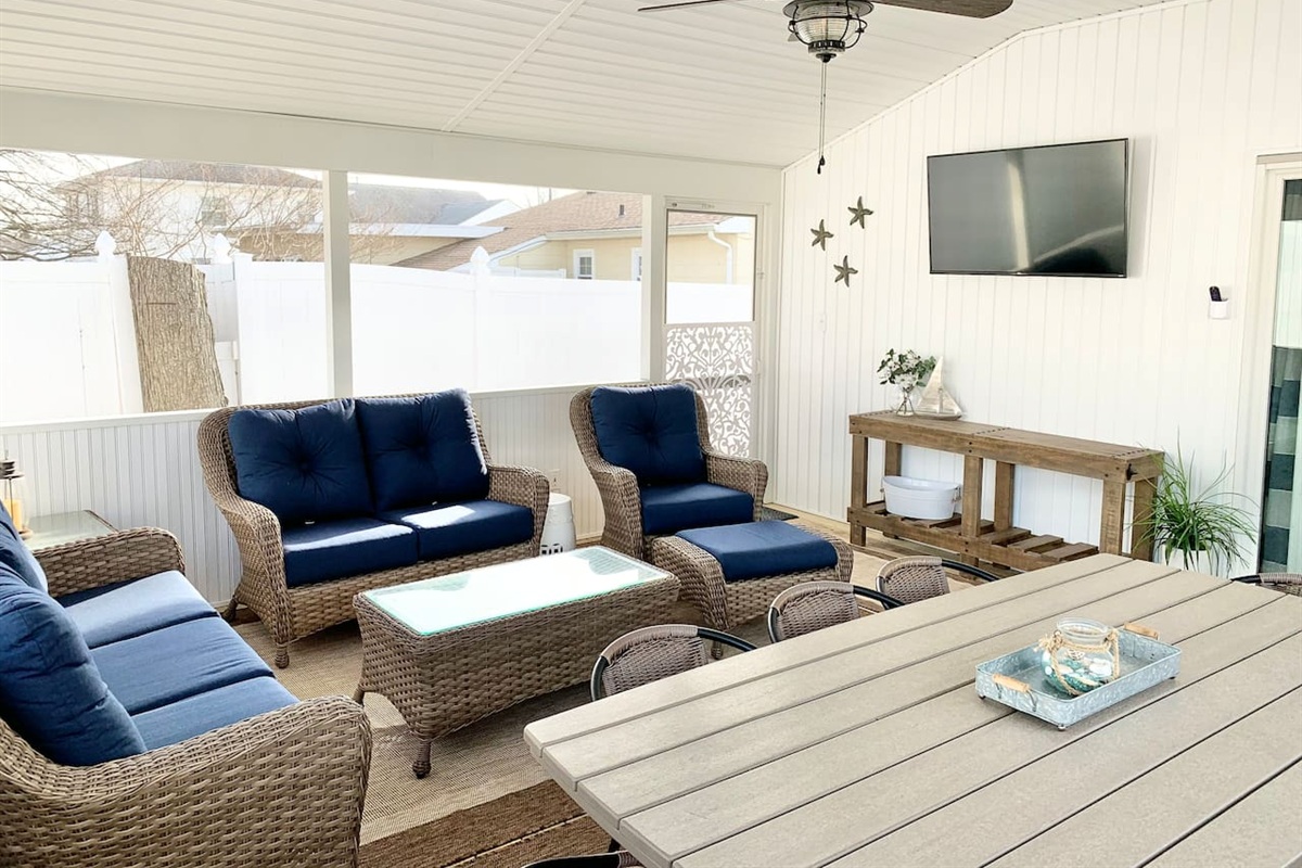 Experience the best of indoor-outdoor living in our screened-in sunroom. Kick back on navy wicker seating to watch the game or enjoy a meal at the large dining table—all while staying protected from the elements in a bright, coastal setting.