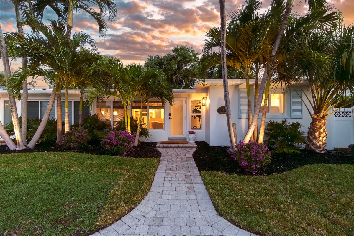 Arrive in style. This beautifully updated Palm Beach-style exterior welcomes you home with lush landscaping and a warm coastal glow.