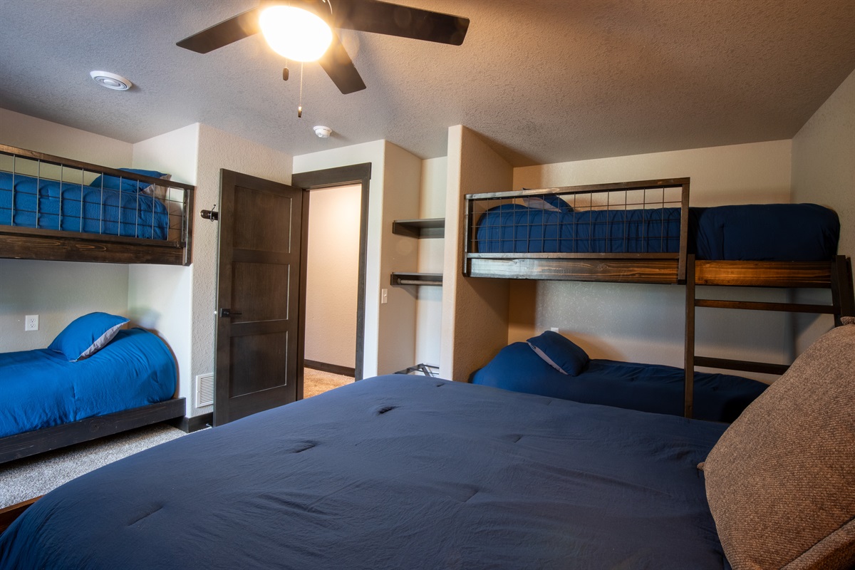 This lower-level room sleeps up to six with a queen bed and 2 sets of twin bunks—perfect for families, cousins, or a fun sleepover-style setup for the kids.