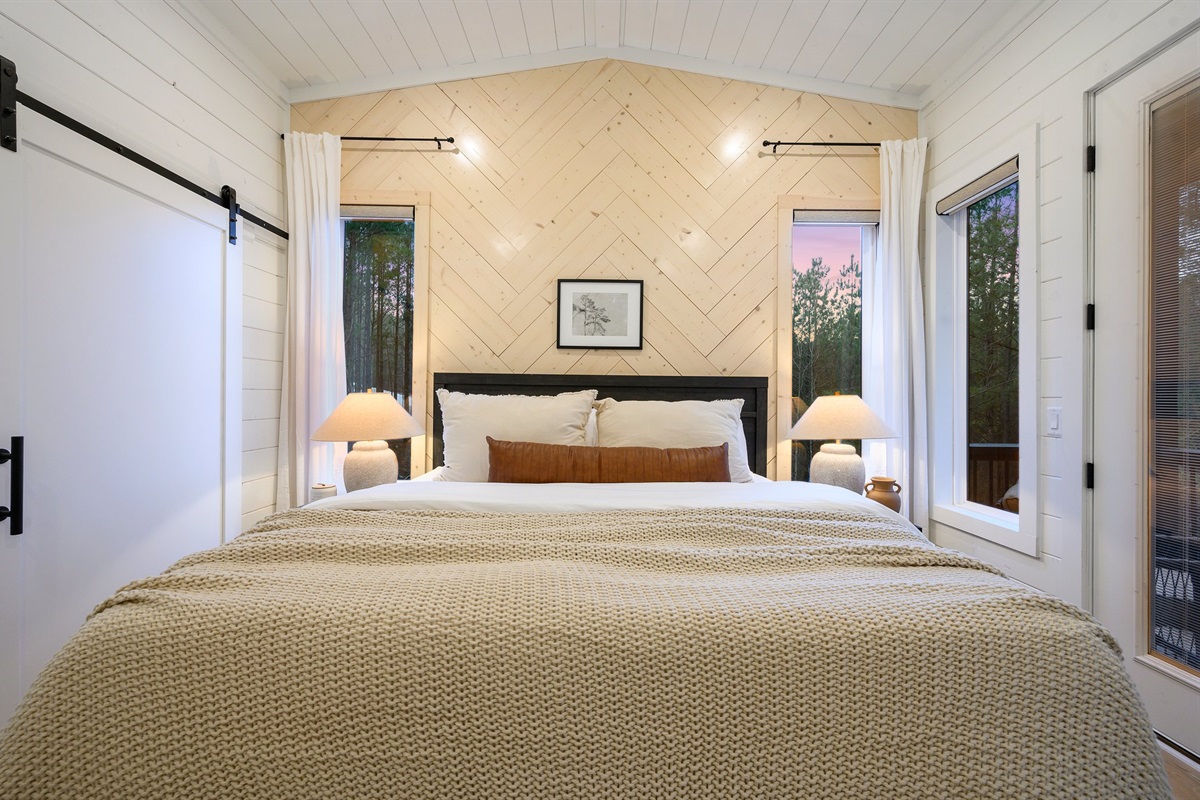 Unwind in this serene bedroom featuring a king bed and warm wood accent wall.