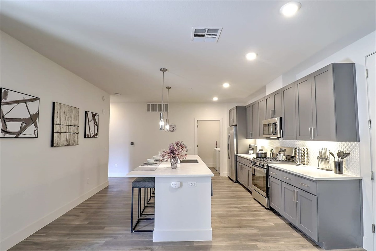 - Experience an open kitchen with modern gray cabinetry and polished counters   - Designed for convenience with stainless steel appliances and bar seating   - Ideal for cooking, chatting, and creating memorable dining moments together