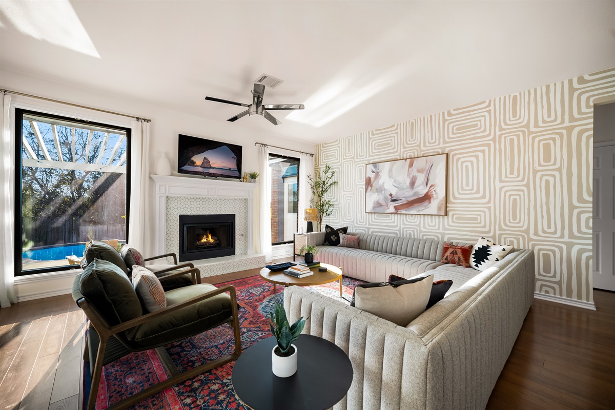 Inviting living room with aesthetic wallpaper, wooden floors, and a poolside view.