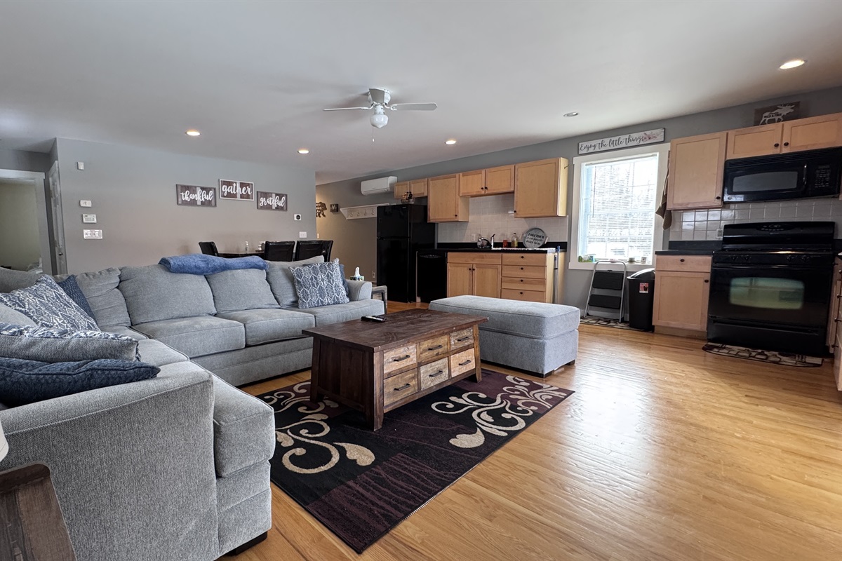Living room with sizeable L-shaped couch with open concept to kitchen and dining area