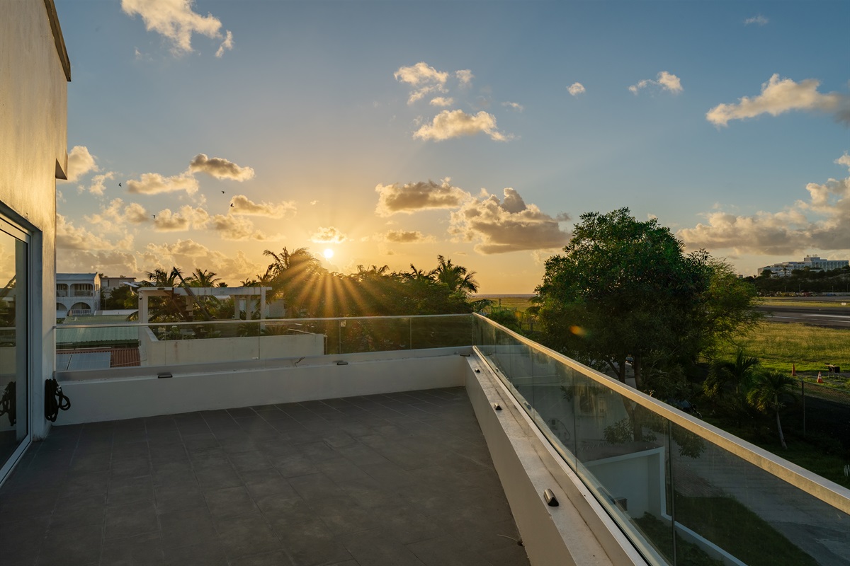 Your massive private deck with glass railings and front-row views of the runway and sunset